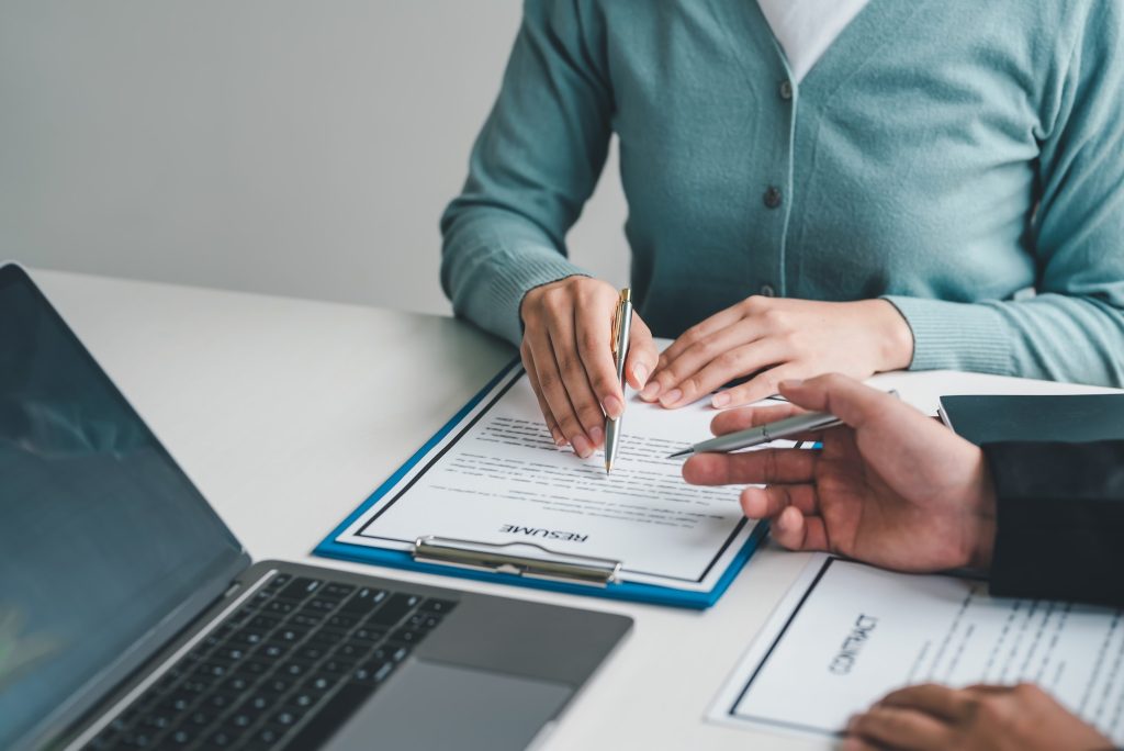 Image of a woman hand pointing at a document about applying for a job to the supervisor at the offic