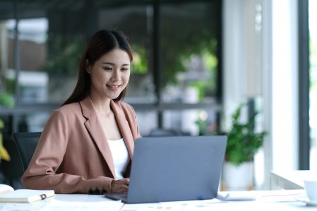 Charming asian businesswoman sitting working on laptop in office.